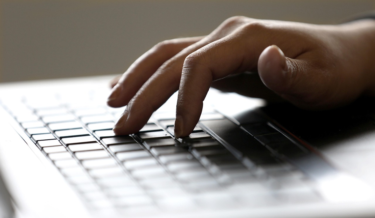 Hands typing on a laptop keyboard